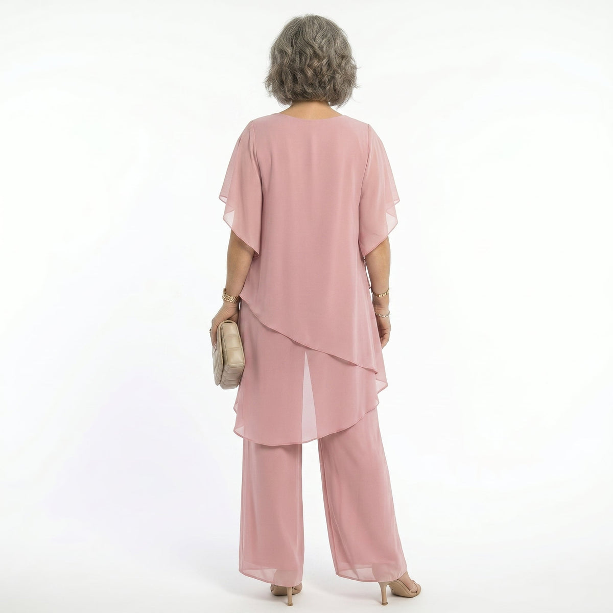 Vista trasera de mujer con conjunto Mara Domínguez rosa de dos piezas, blusa de capas asimétricas y pantalón fluido.