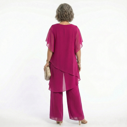 Vista trasera del conjunto Mara Domínguez Ainhoa en fucsia con blusa de capas asimétricas y pantalón fluido elegante