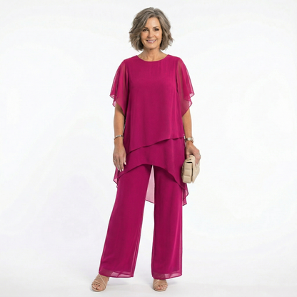 Mujer madura vistiendo conjunto Mara Domínguez de dos piezas color fucsia con blusa de capas y pantalón fluido