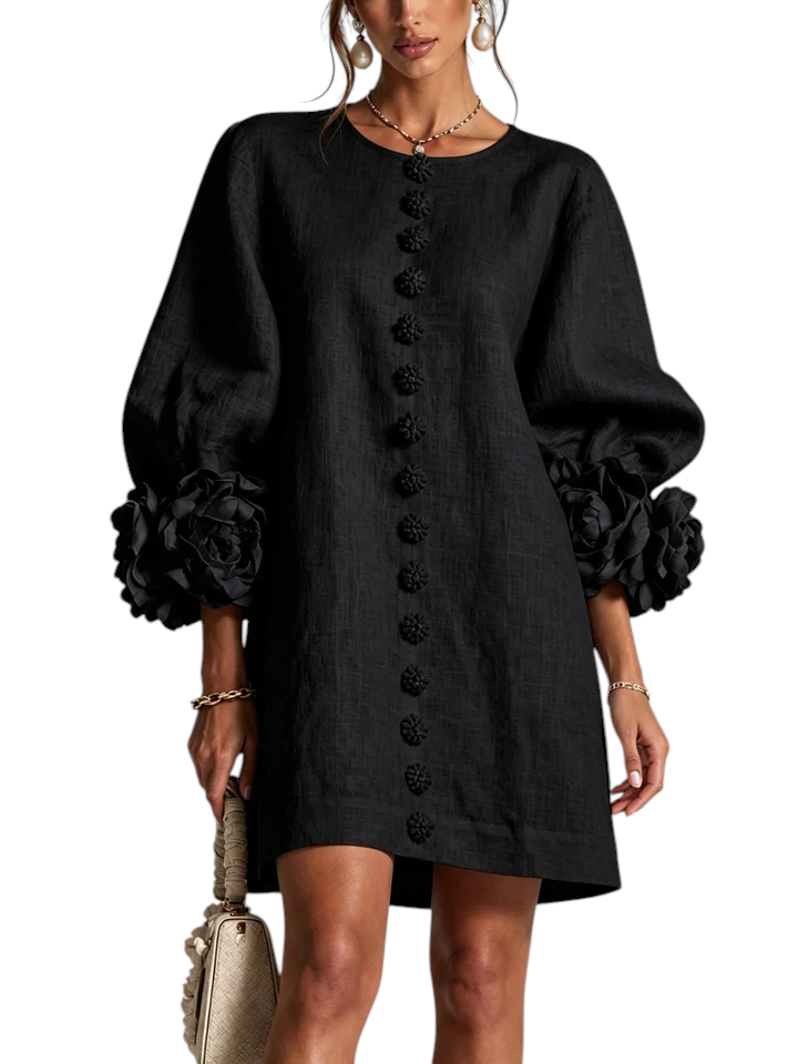 Vestido corto negro de lino Mara Domínguez con mangas abullonadas, detalles florales en puños y botones frontales.