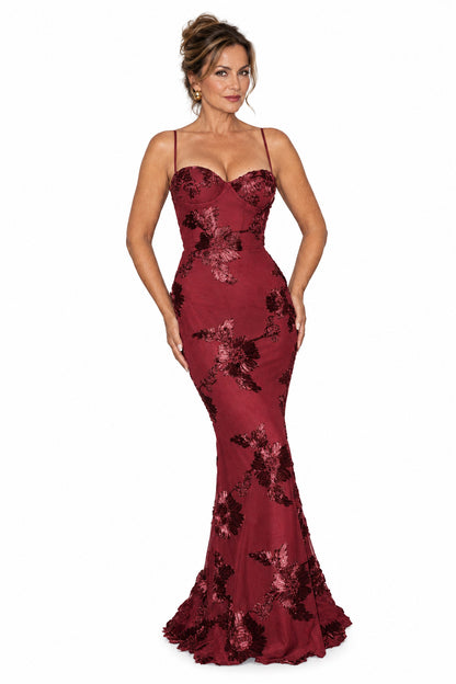 Modelo posando con vestido largo Mara Domínguez color burdeos ajustado con escote corsé y bordados florales oscuros