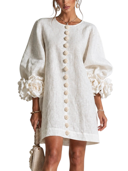 Vestido corto de lino color crema Mara Domínguez con mangas abullonadas y detalles de flores artesanales en los puños.